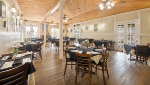 A spacious dining area with wooden floors and high ceilings, featuring multiple tables and chairs arranged for dining. - The Historic Island Hotel of Cedar Key (Cedar Key)