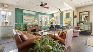 A room with green walls, a piano, leather sofas, and a mirror. - The Downtown Historic Island Hotel (Cedar Key)