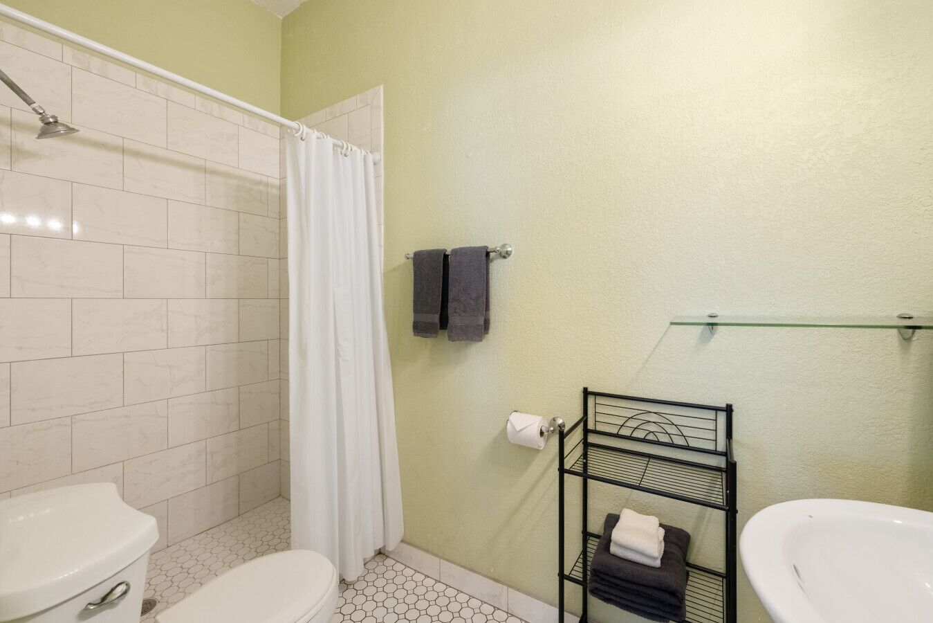 A bathroom with a shower, toilet, and sink.