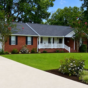 A two-story house with a front porch, brick exterior, and a well-maintained lawn.