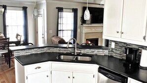 Cocina moderna con armarios blancos, encimera negra y pileta de acero inoxidable.