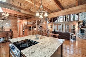 A spacious kitchen with granite countertops, a central island, and a stone fireplace. - GatlinByrd Lodge! Indoor Pool/Hot Tub/Pet Friendly (Sevierville)