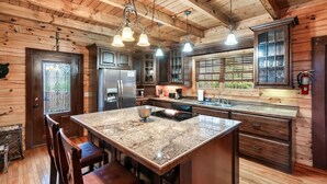 Una cocina con paredes de madera, una isla de granito e iluminación colgante.
