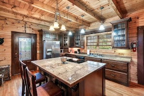 A kitchen with wooden walls, a granite island, and pendant lighting. - GatlinByrd Lodge! Indoor Pool/Hot Tub/Pet Friendly (Sevierville)
