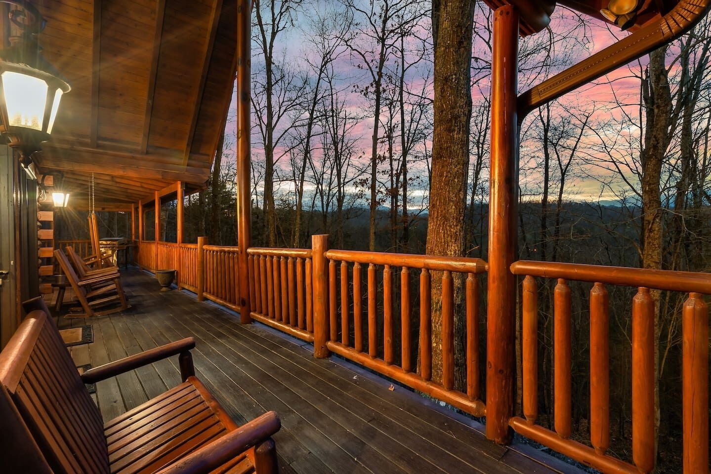 A wooden deck with railings, benches, and a hanging light fixture.