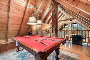 A pool table in a wooden room with a sloped ceiling and a view of the outdoors. - GatlinByrd Lodge! Indoor Pool/Hot Tub/Pet Friendly (Sevierville)