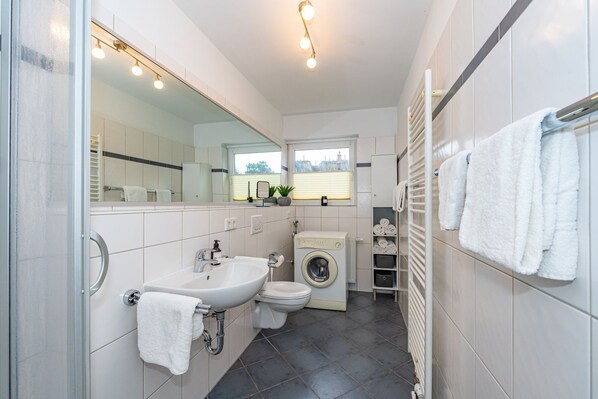 A modern bathroom with a sink, toilet, and washing machine. - Emma - Quiet first floor apartment with terrace for max. 4 persons. (Westerland)