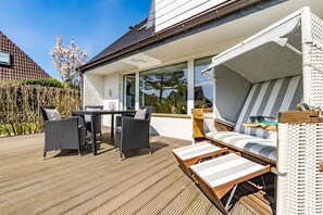 A modern outdoor deck with wicker furniture, a wooden table, and striped lounge chairs. - Emma - Quiet first floor apartment with terrace for max. 4 persons. (Westerland)