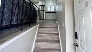 A staircase with a wooden finish, a metal railing, and a white door with a lock. - Modern 2BR Stylish Retreat A Upstairs (Atlanta)