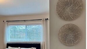 A bedroom with a bed, a window with blinds, and three wall-mounted decorative items. - Modern 2BR Stylish Retreat A Upstairs (Atlanta)