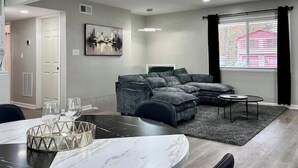 A modern living room with a sectional sofa, a dining table with chairs, and a small side table. - Modern 2BR Stylish Retreat A Upstairs (Atlanta)