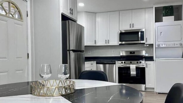 A modern kitchen with white cabinets, stainless steel appliances, and a marble dining table. - Modern 2BR Stylish Retreat A Upstairs (Atlanta)
