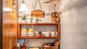 A shelf with kitchenware, a hanging sign, and a vase with dried plants.