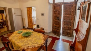 A dining area with a table set for four, a refrigerator, and a wooden door.