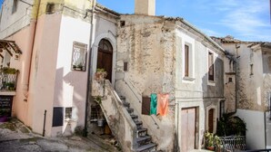 A narrow street with a building featuring a staircase and a small shop at the bottom.