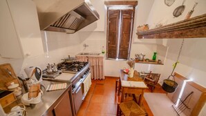 A compact kitchen with a stove, sink, and wooden dining table.