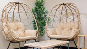 Two wicker chairs with cushions, a small wooden table, and a potted plant in a corner. - Zen Den Oasis: Retreat in Nature, 4-Bedroom Home on 10 Acres of Private Land (Cottage Grove)