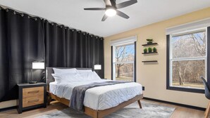 A bedroom with a bed, bedside tables, a ceiling fan, and large windows. - Zen Den Oasis: Retreat in Nature, 4-Bedroom Home on 10 Acres of Private Land (Cottage Grove)