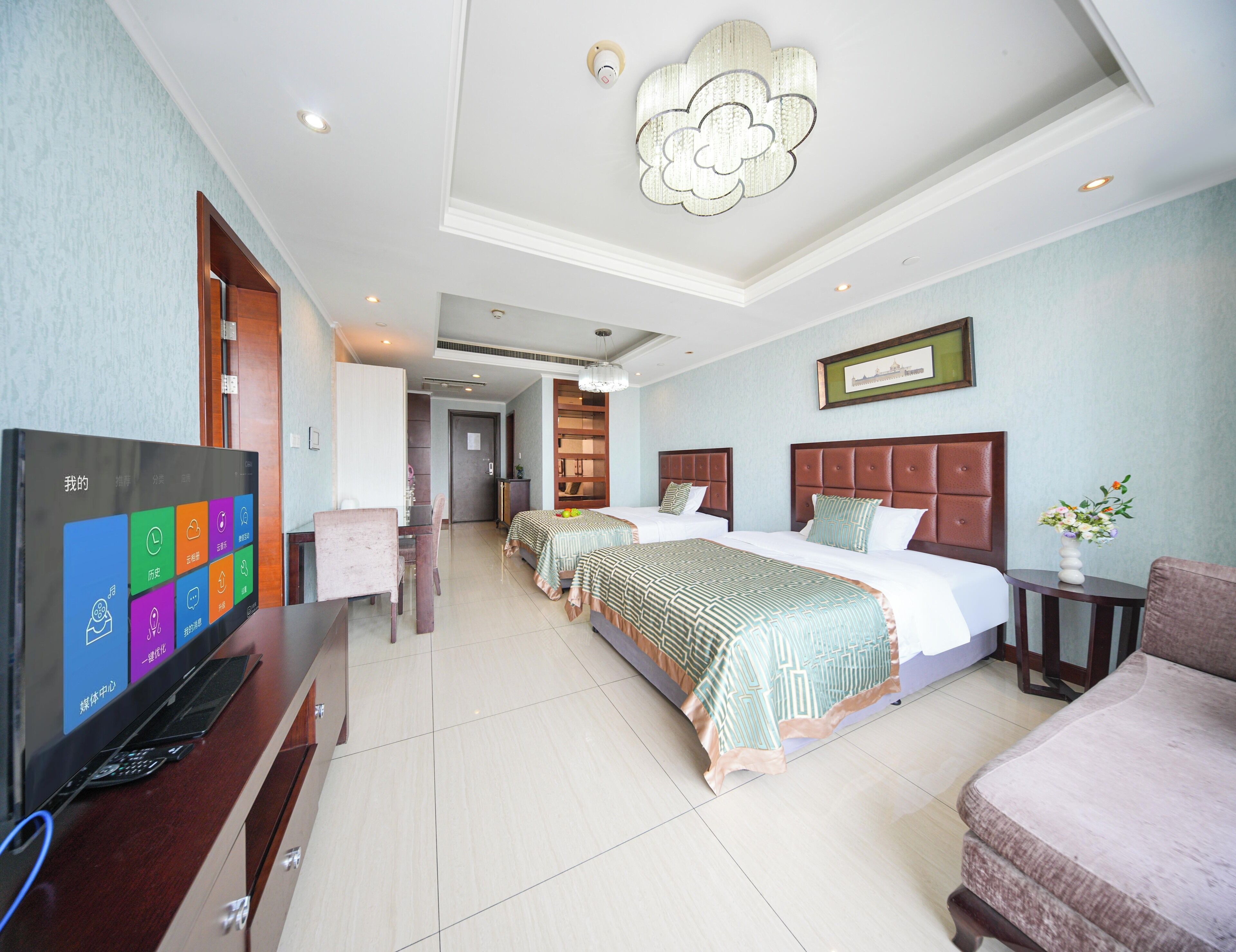 Habitación de hotel con televisión, dos camas, escritorio y una silla.