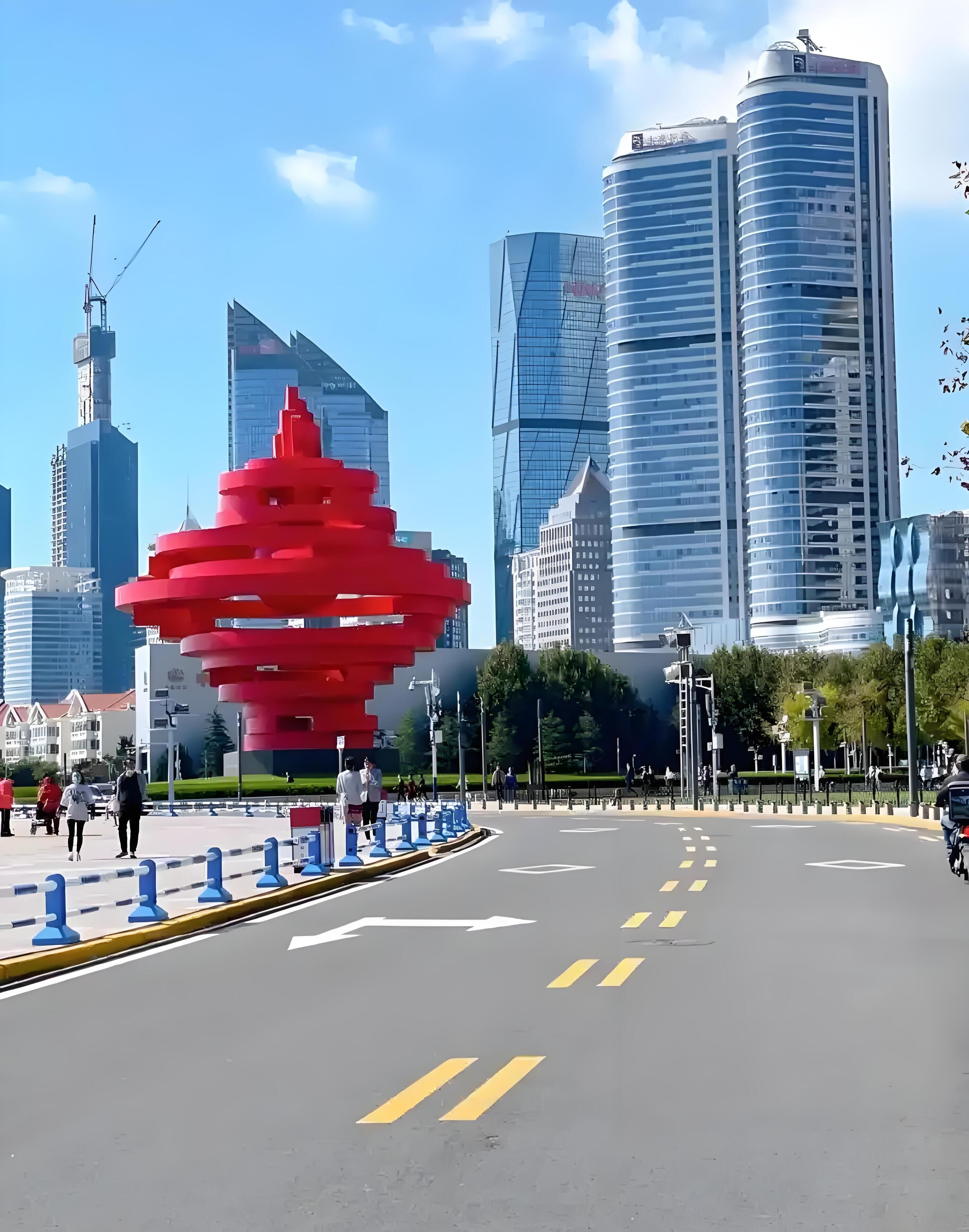 A cityscape with modern buildings, a prominent red sculpture, and a clear sky.