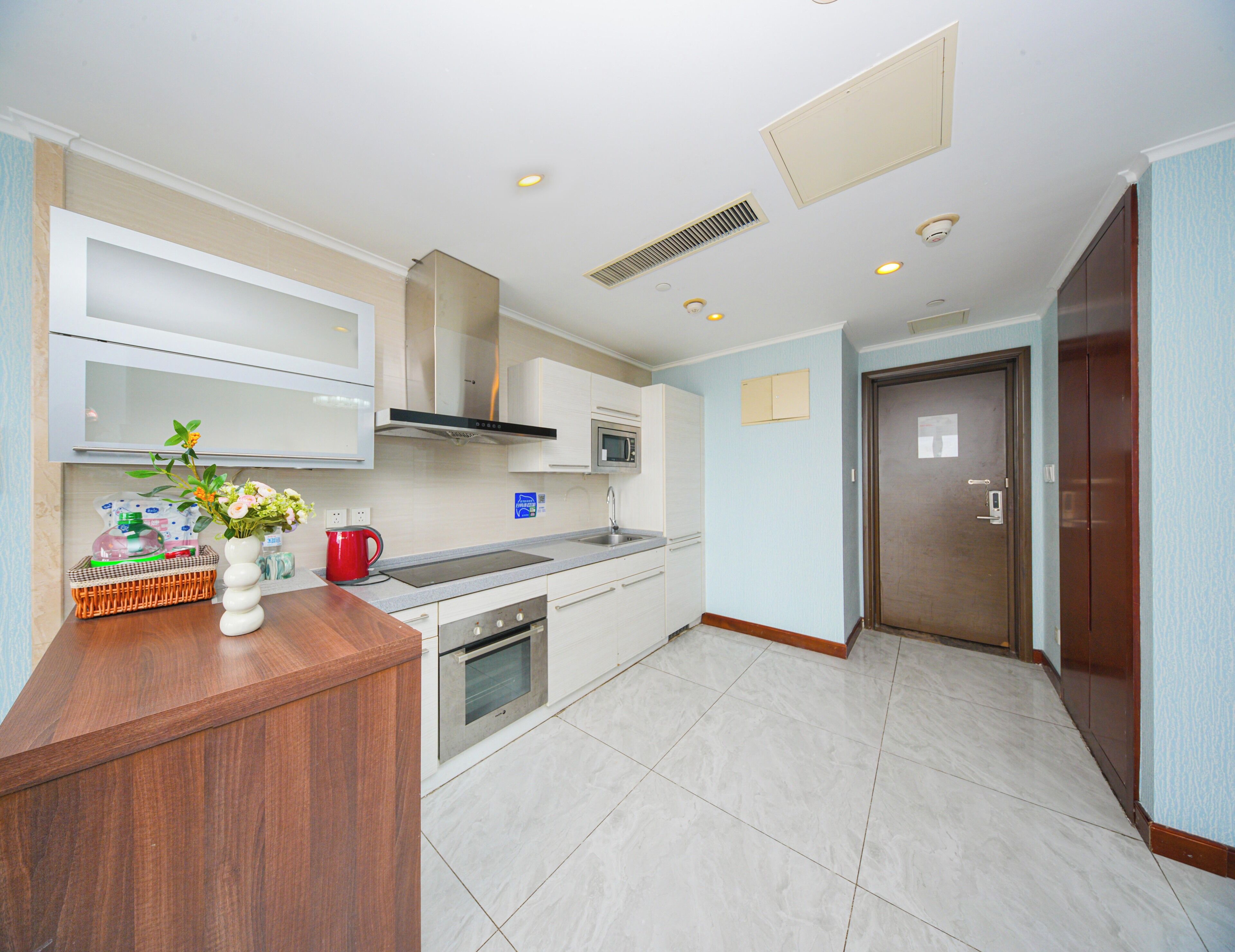 A modern kitchen with white cabinets, a wooden countertop, a built-in oven, and a stainless steel sink.
