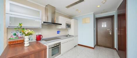 A modern kitchen with white cabinets, a wooden countertop, a built-in oven, and a stainless steel sink.