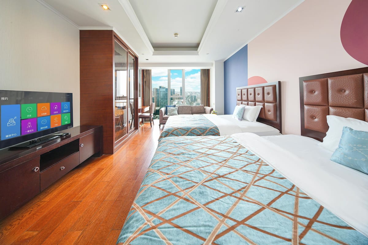 Une chambre d’hôtel avec un grand lit, une télévision, un bureau et une vue sur la ville.