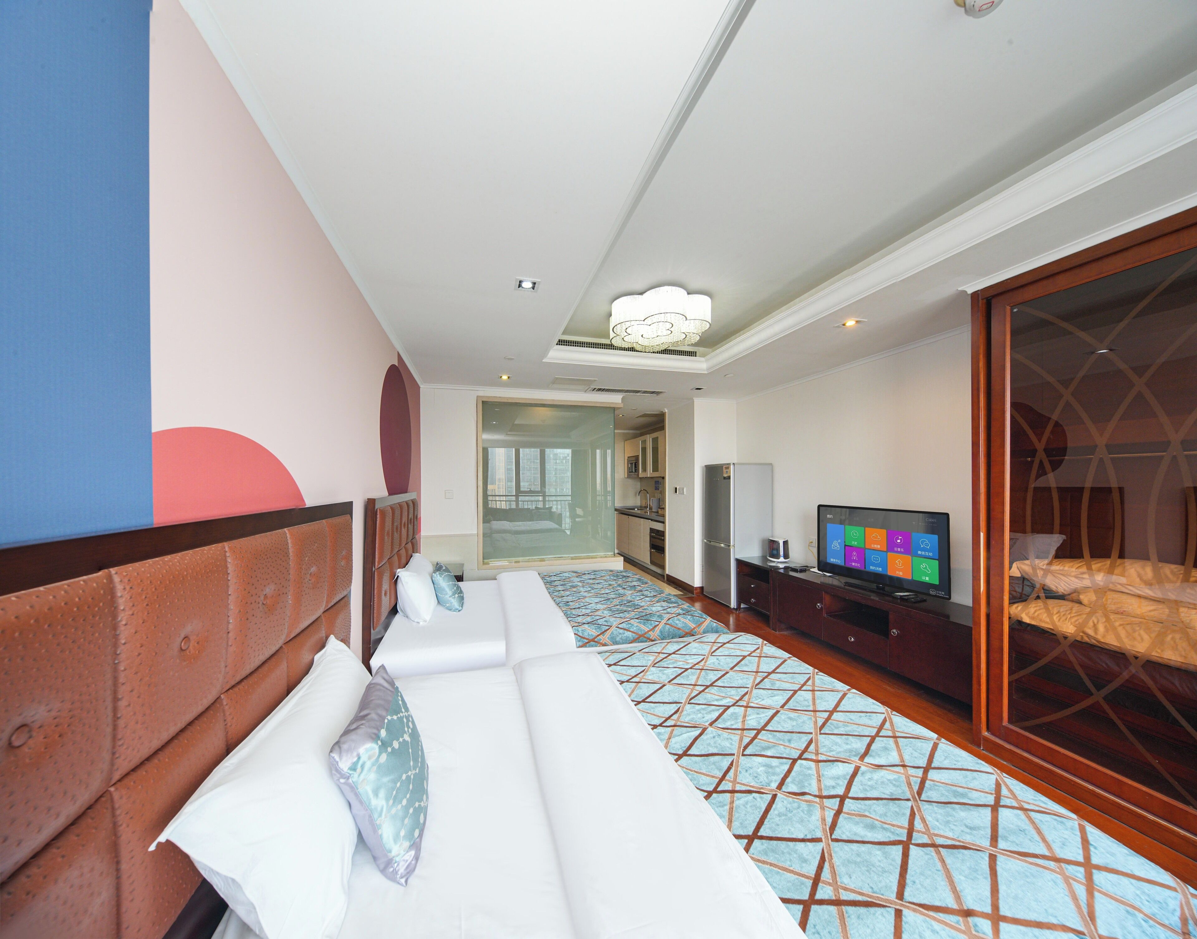 Habitación de hotel con cama, televisor, escritorio y baño visible a través de una puerta de cristal.