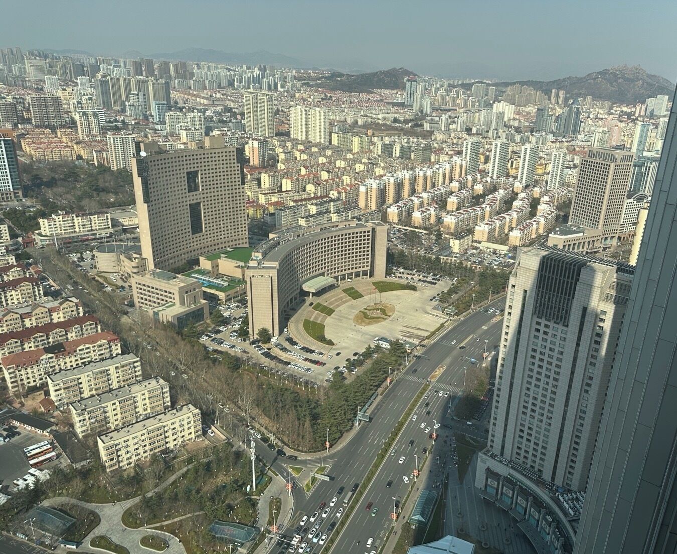 Zona urbana con edificios residenciales y comerciales, un cruce de múltiples carriles en el centro y una amplia plaza abierta.
