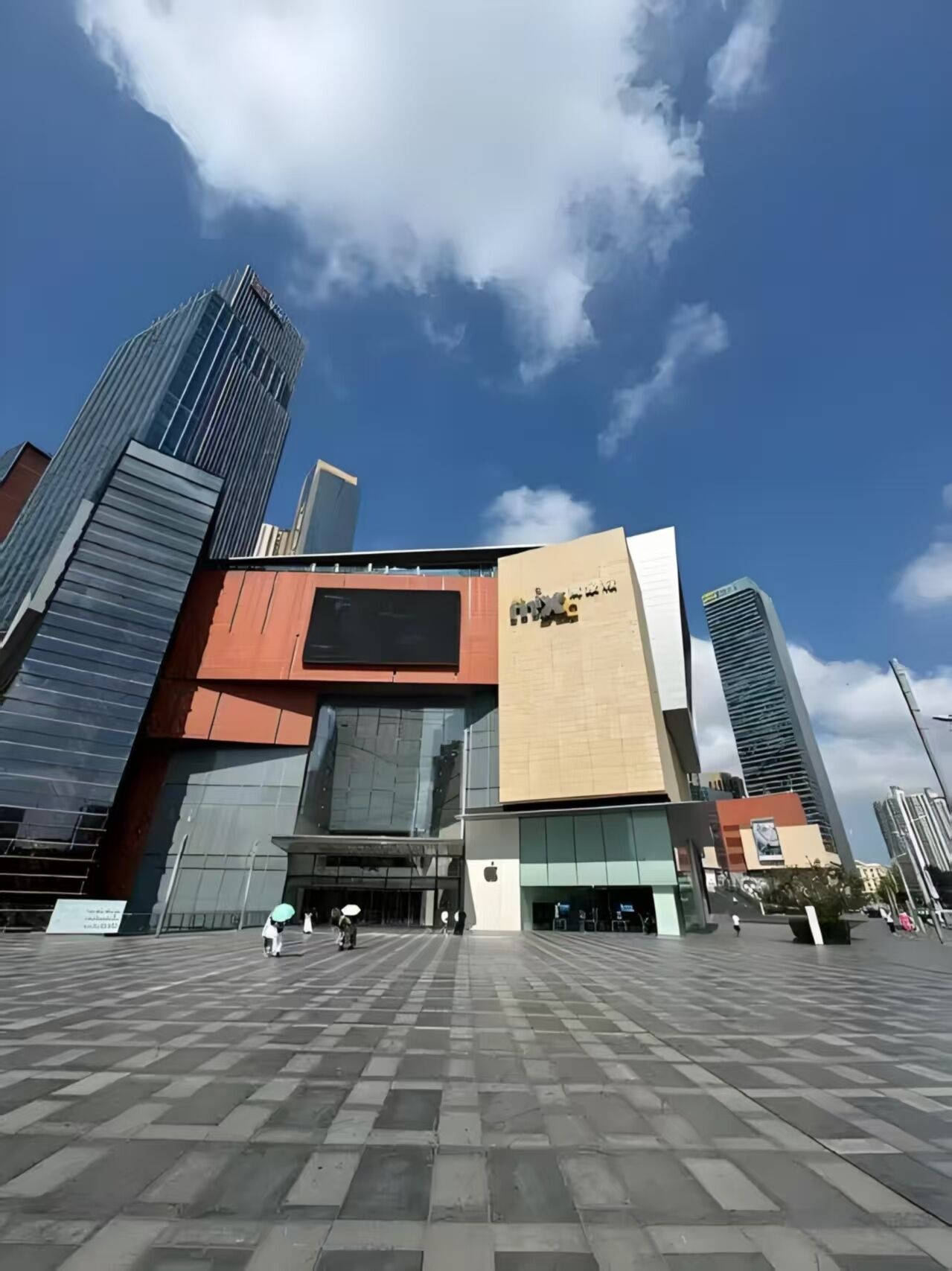 A modern building with a prominent 'mix' sign, featuring a mix of glass and metal architecture, set against a clear blue sky.