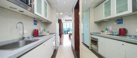 A modern kitchen with stainless steel appliances, white cabinetry, and a marble floor.
