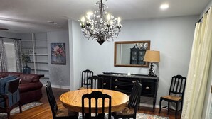 A dining area with a round wooden table, black chairs, a chandelier, a patterned rug, and a mirror above the table. - Gorgeous quiet and cozy 3 bedroom/ 2 bathroom home awaits you! (Uvalde)