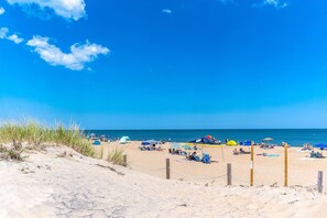 A beach with tents and umbrellas, sandy dunes, and the ocean.