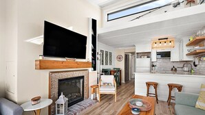 En moderne stue med pejs, et fladskærms-tv og et spiseområde med barstole.