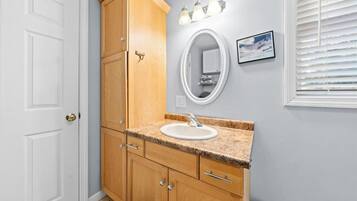 A bathroom with a wooden vanity, a white sink, and a mirror.