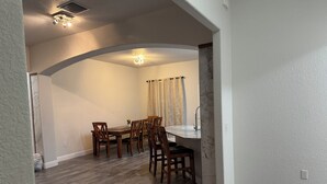 A dining area with a wooden table and chairs, a marble countertop, and a ceiling light fixture. - Newer Construction Home in Port Richey, High Ceilings Screened Lanai & Lake View (Port Richey)