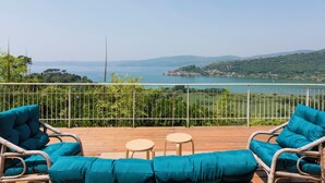 A wooden deck with wicker furniture and a view of a lake and hills.