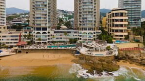 A coastal hotel with multiple high-rise buildings, a beach, and a pool area. - Suite 1808 by Suites Victoria Acapulco (Acapulco de Juárez)