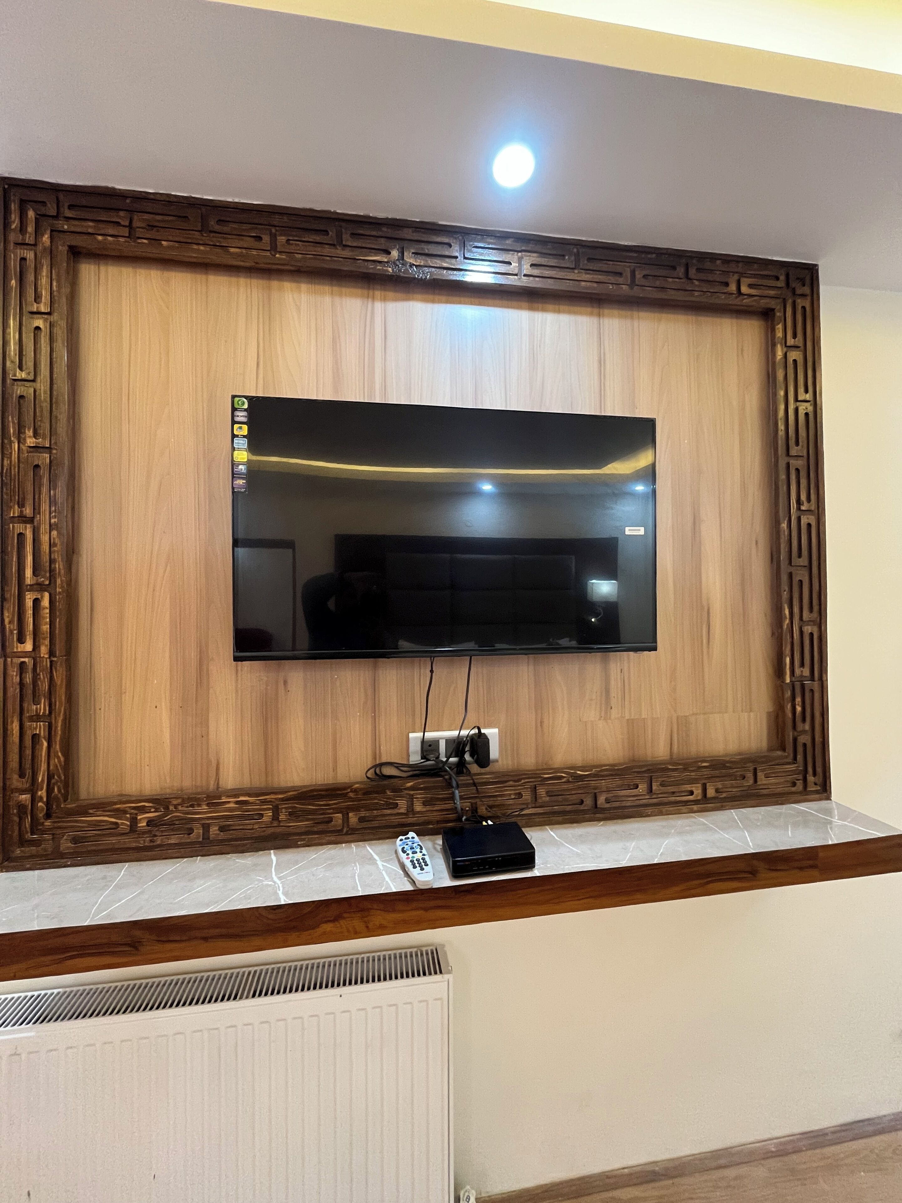 A flat-screen TV mounted on a wooden wall with a decorative frame.