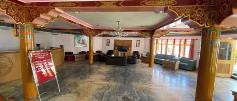 A hotel lobby with a marble floor, a reception desk, and a seating area with sofas and chairs.