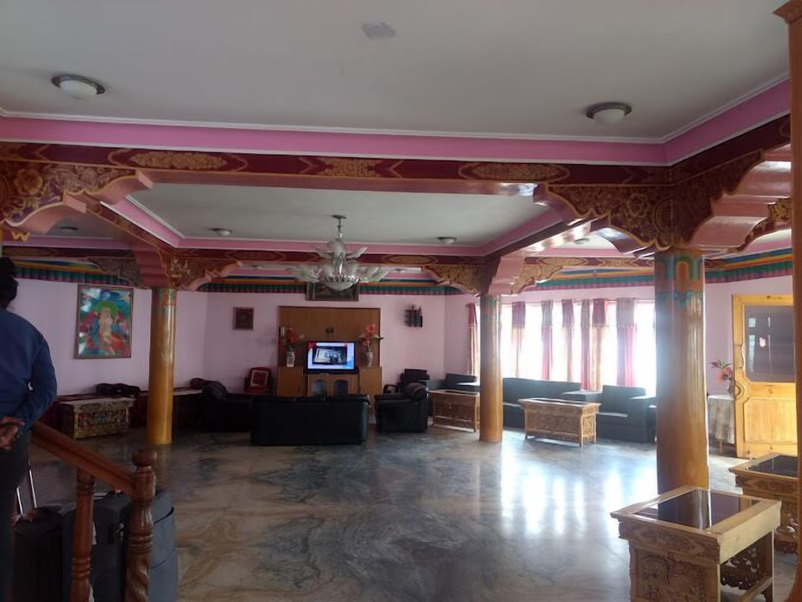 A spacious lobby with a television, seating area, and decorative pillars.