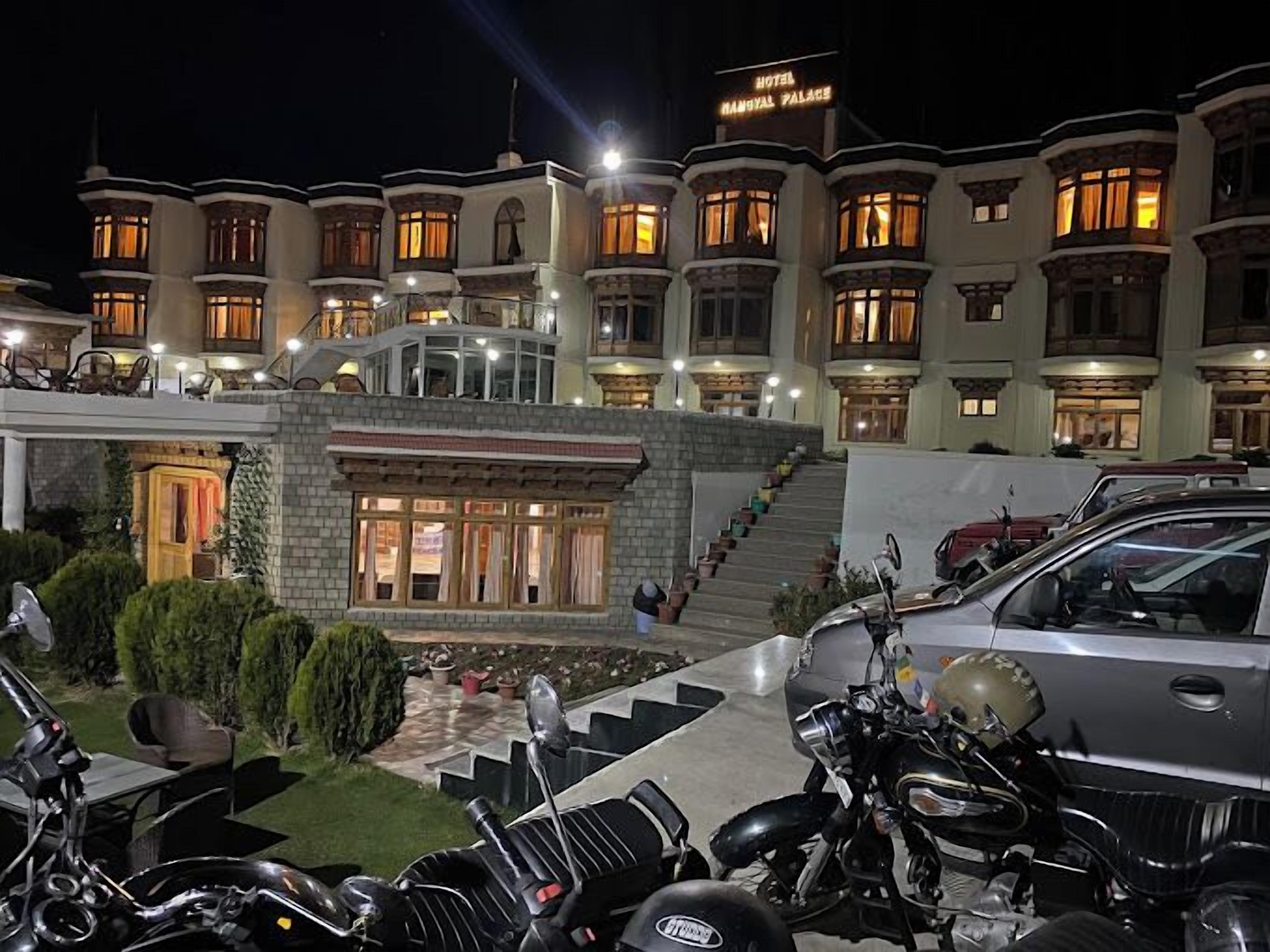 A large, multi-story hotel with a grand entrance, a well-lit facade, and a staircase leading to the main entrance.