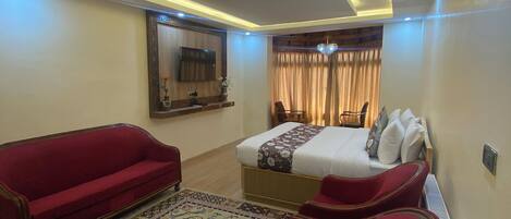 A hotel room with a bed, red sofa, and a patterned rug.