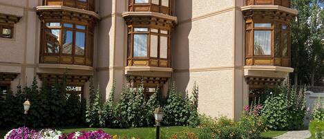 Un bâtiment doté d’une tourelle d’angle, de grandes fenêtres et d’un jardin fleuri.