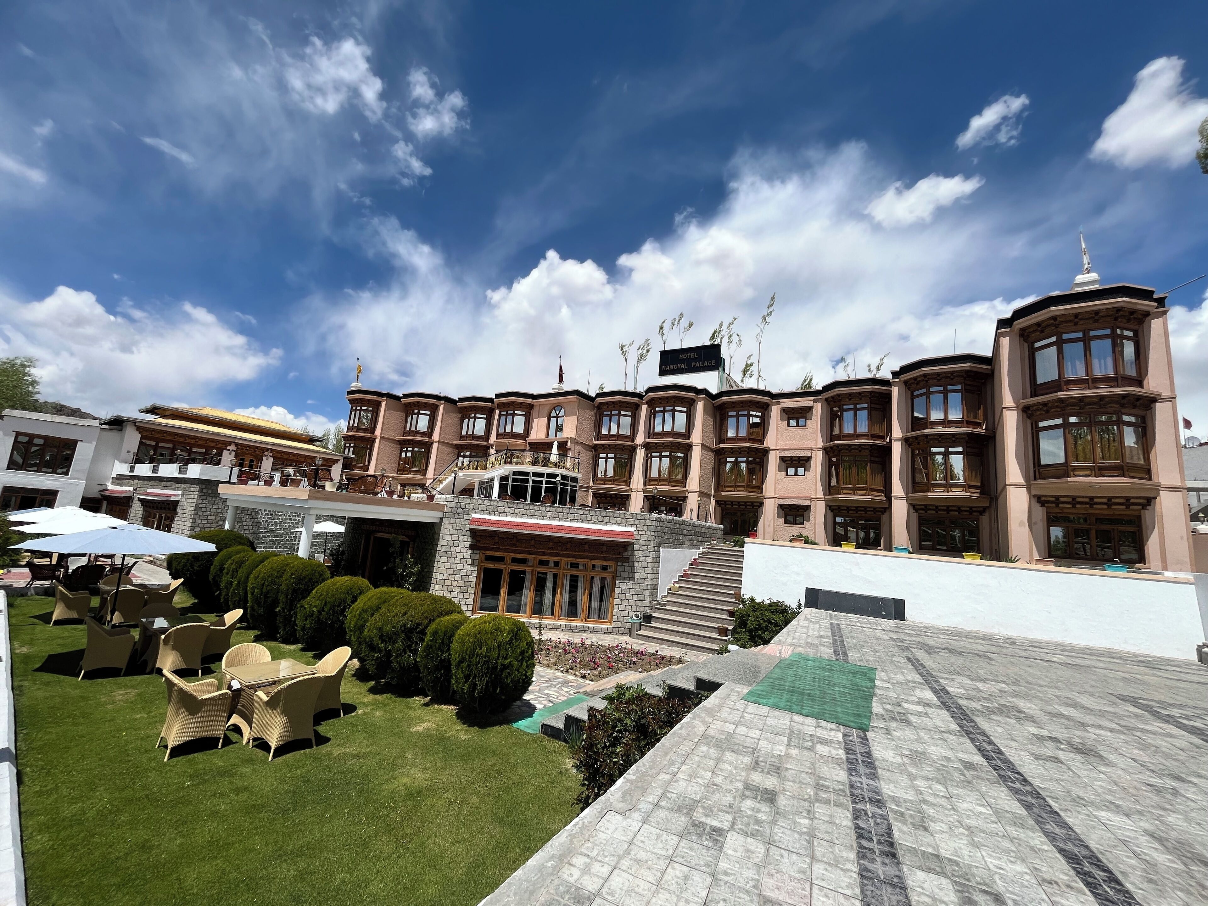 A hotel with a large, multi-story building, a well-maintained lawn, and outdoor seating area.