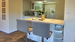 Una cocina moderna con una isla central, dos taburetes de bar y decoración en la pared.