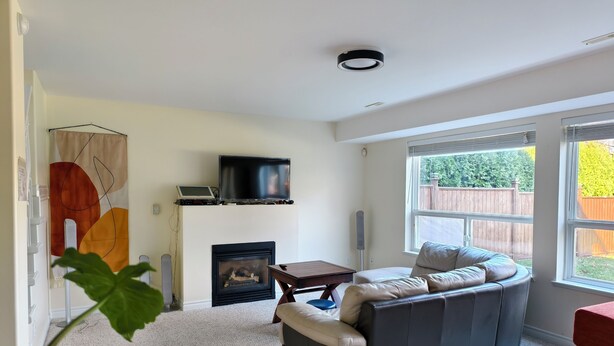 Una sala de estar con chimenea, un sofá, un televisor y un ventanal grande.