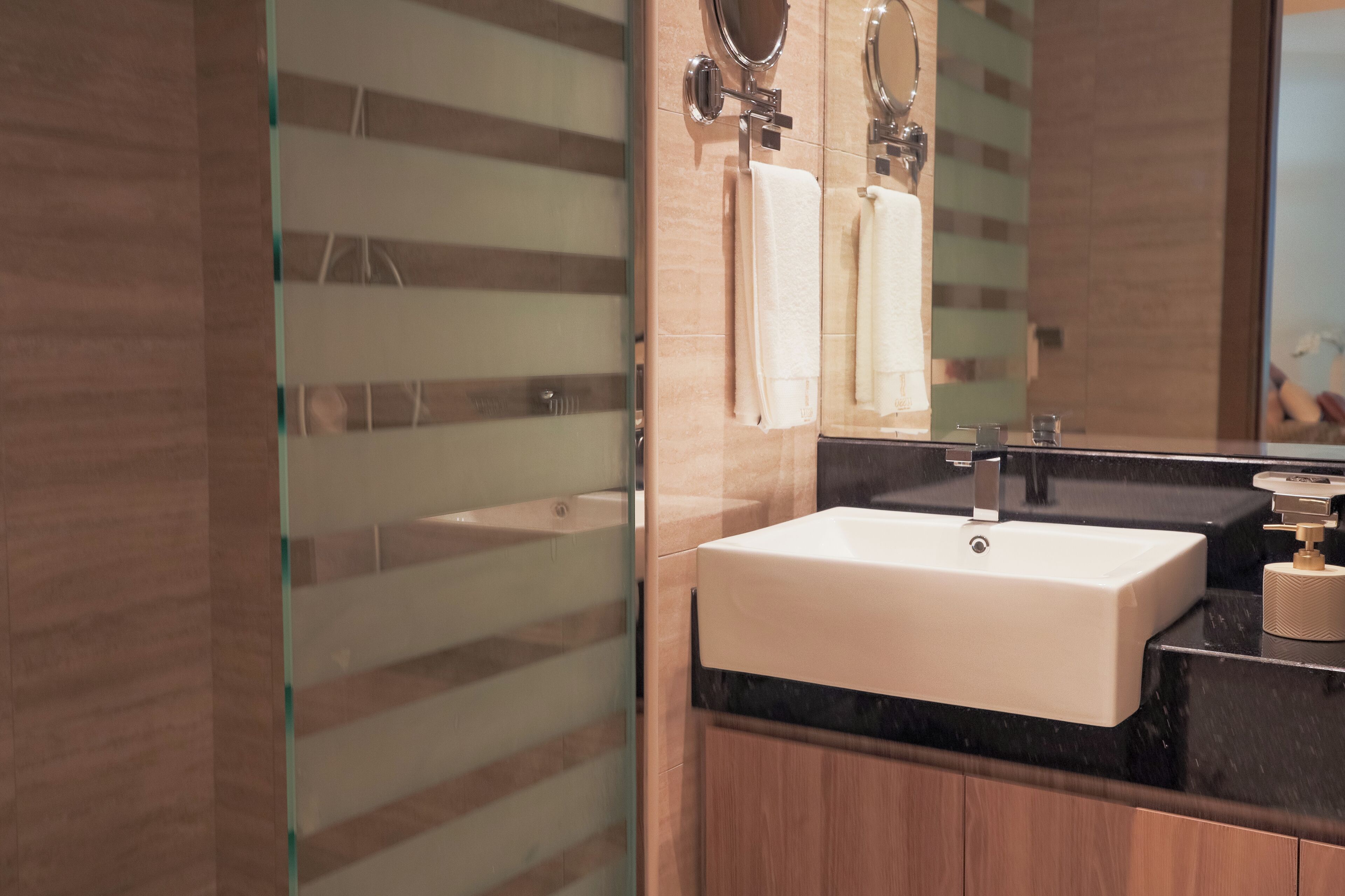 A modern bathroom with a large mirror, a sink, and a glass shower enclosure.