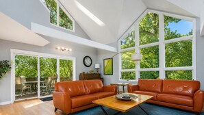 A spacious living room with a large window, a sofa set, a coffee table, and a clock on the wall. - 3 bedroom 3 bath, expansive views Treehouse feel (Galena)
