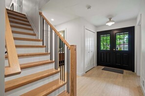A staircase with wooden steps and black railings, a black door with glass panels, and a light-colored floor.